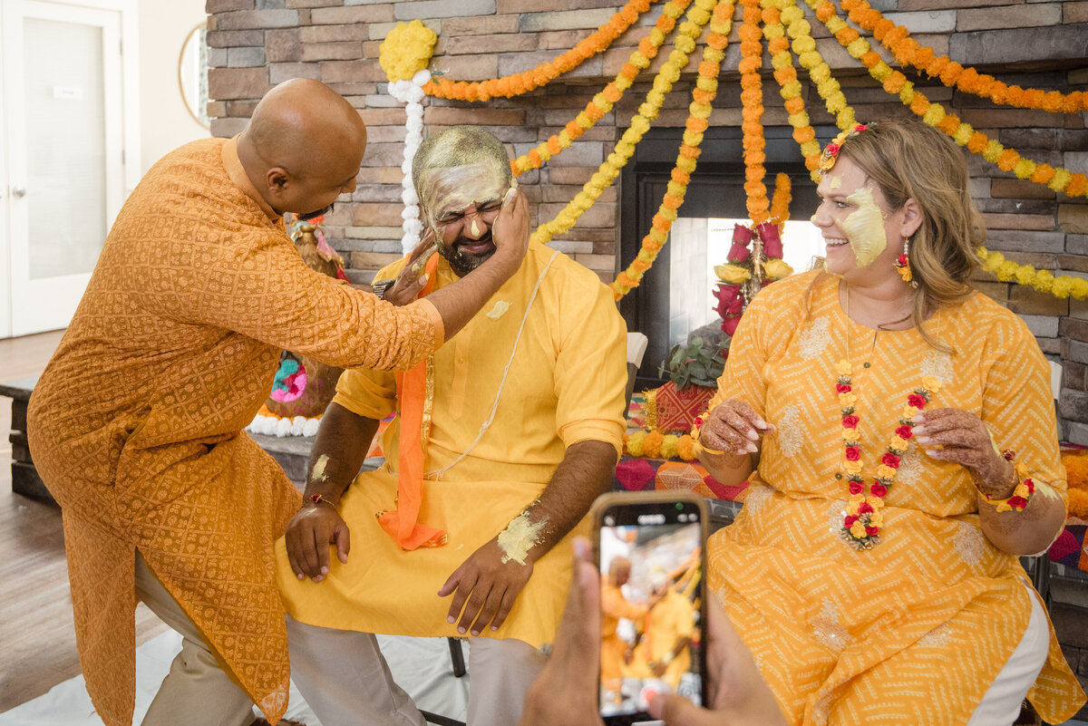 Joyful Haldi ceremony at Le Méridien Charlotte with bride and groom covered in turmeric, captured by a professional Indian wedding photographer in Charlotte.