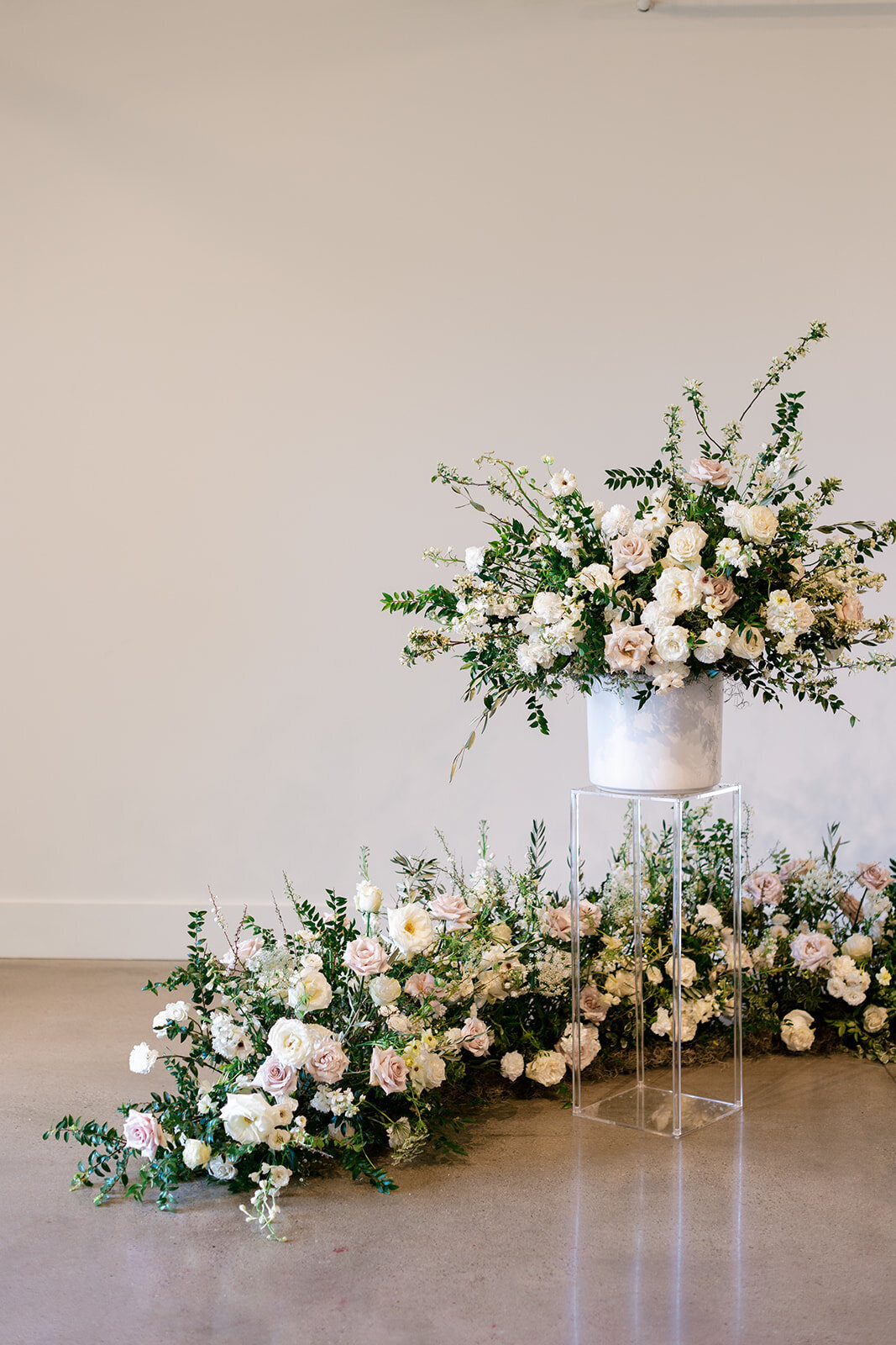 Lush ceremony installation featuring garden urns and meadows with petal heavy roses butterfly ranunculus, delphinium, and Queen Anne’s lace with natural, untamed greenery. Floral hues of white, cream, and blush. Designed by Rosemary and Finch in Nash