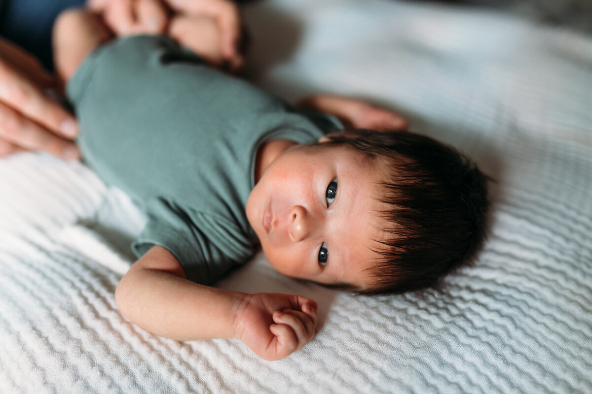 Newborn Photographer,  a baby lays sleeping on the bed