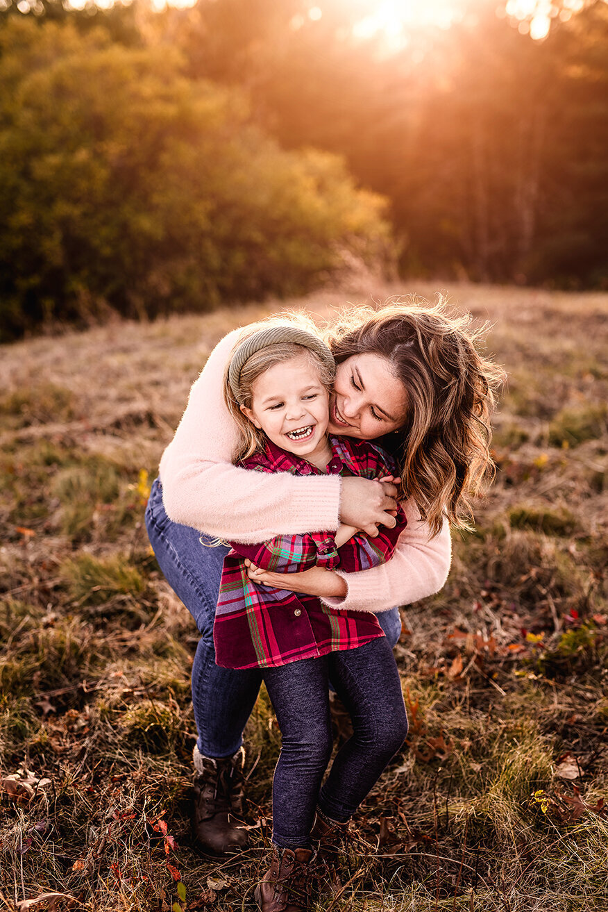 Mom hugging laughing daughter at family photo session in Durham NH by Lisa Smith Photography