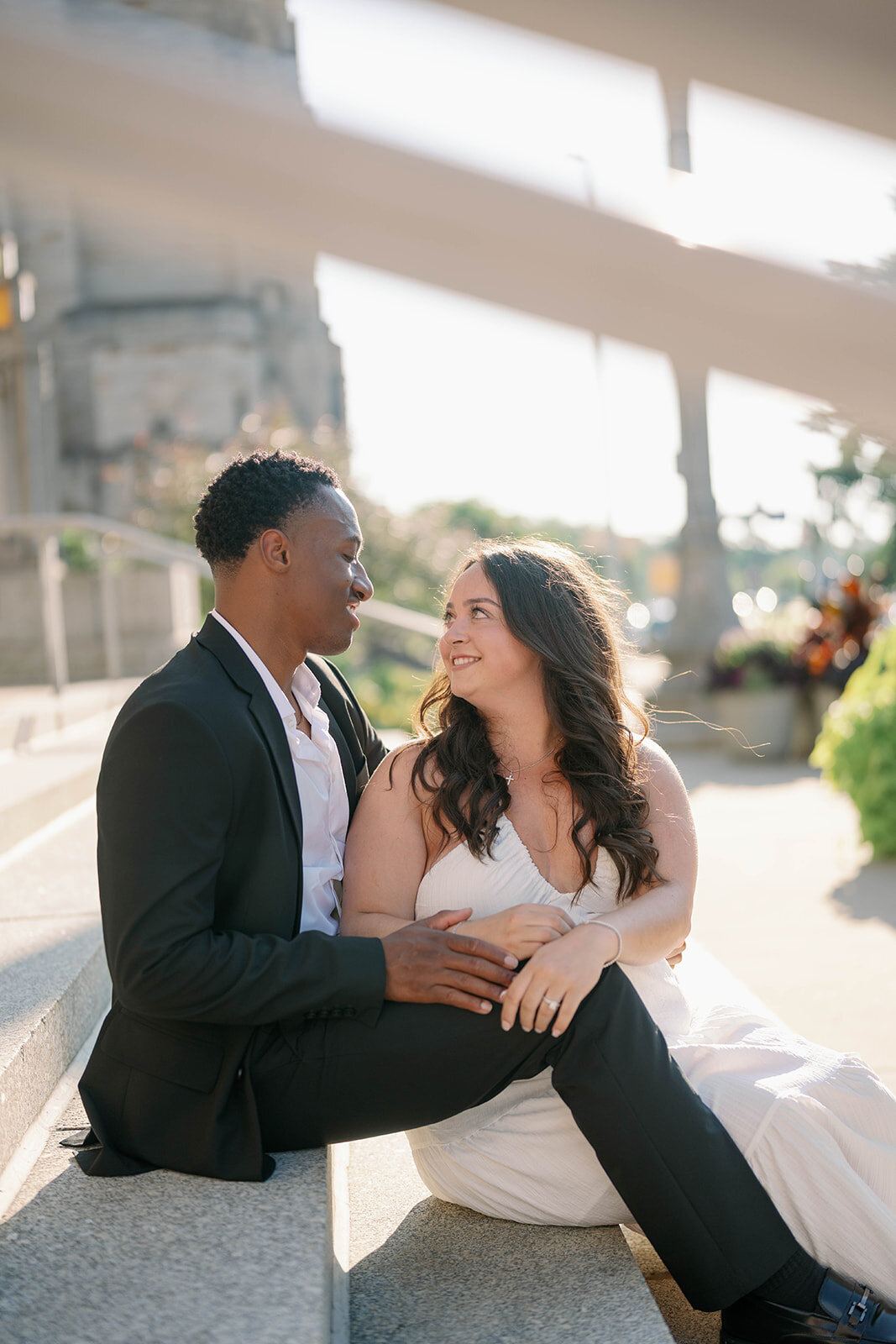 Natural light engagement photo of couple cuddled together on steps in Kalamazoo, Michigan.