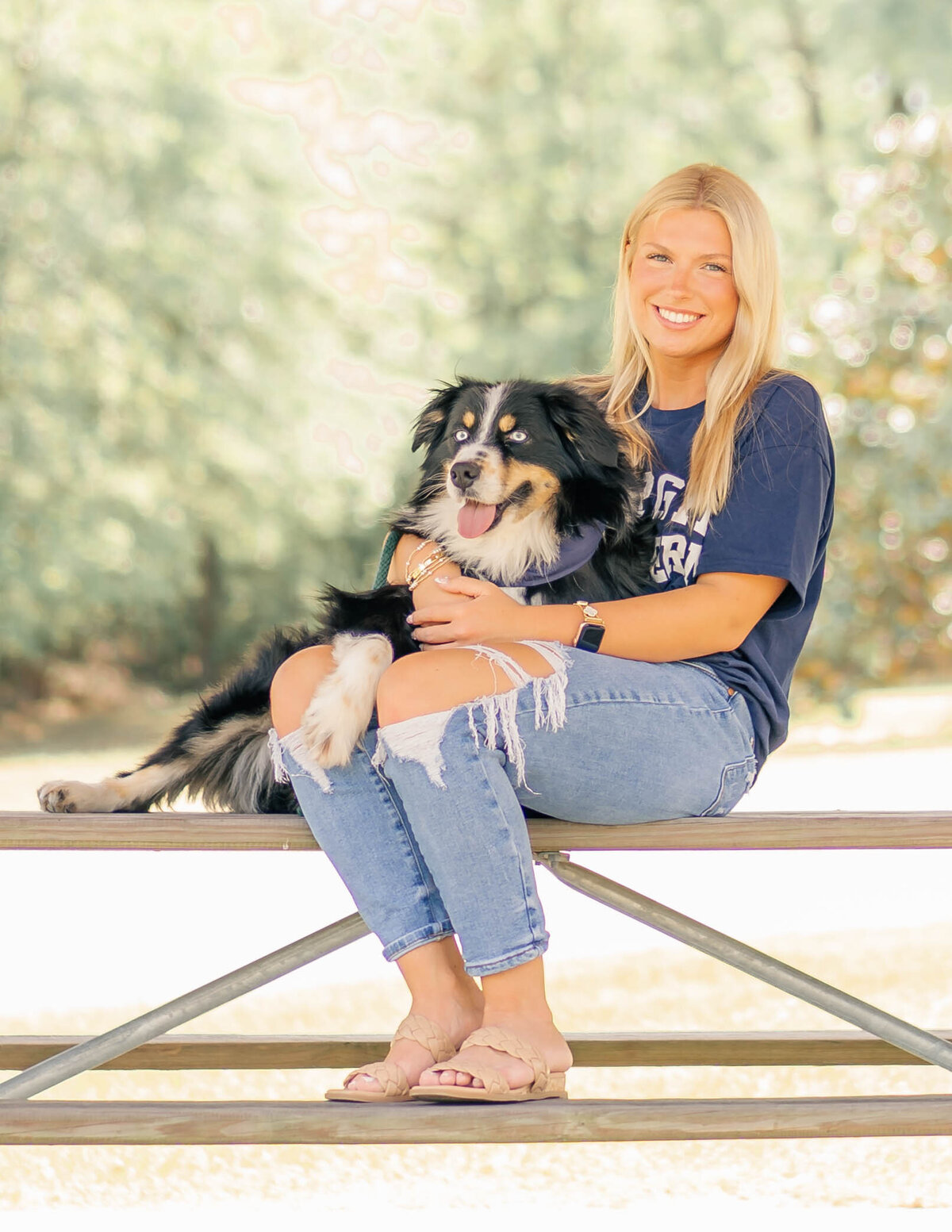 High school senior with her dog sitting on picnic table at a local state park