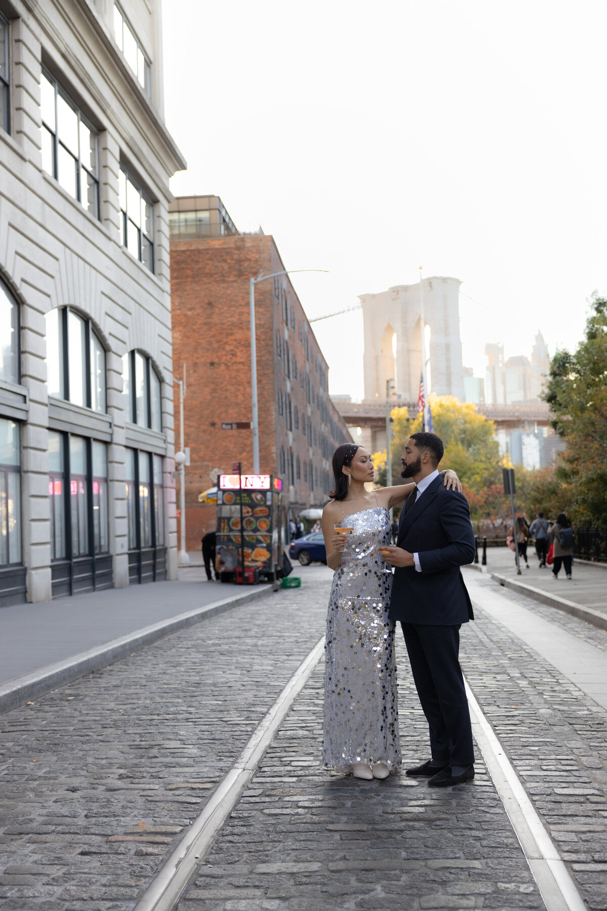 The couple shares a tender moment with the Brooklyn Bridge towering in the background of DUMBO, NYC.