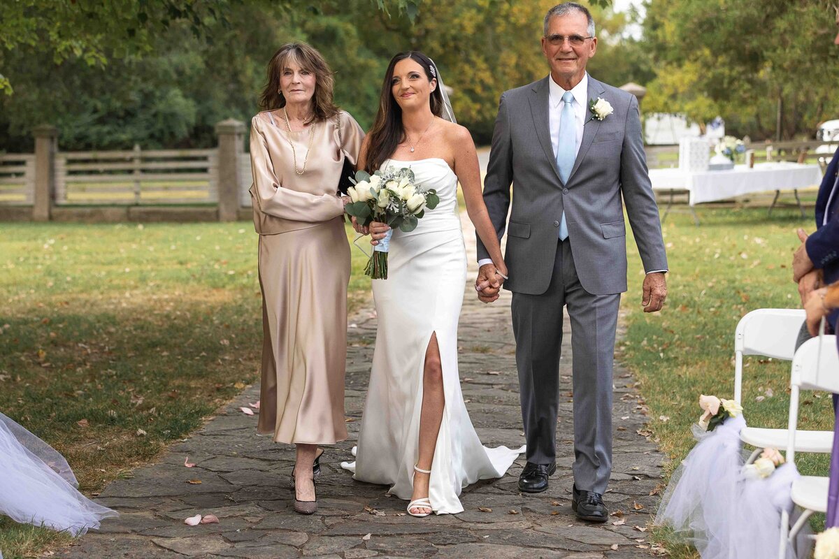 Bride walking down aisle with mother and father