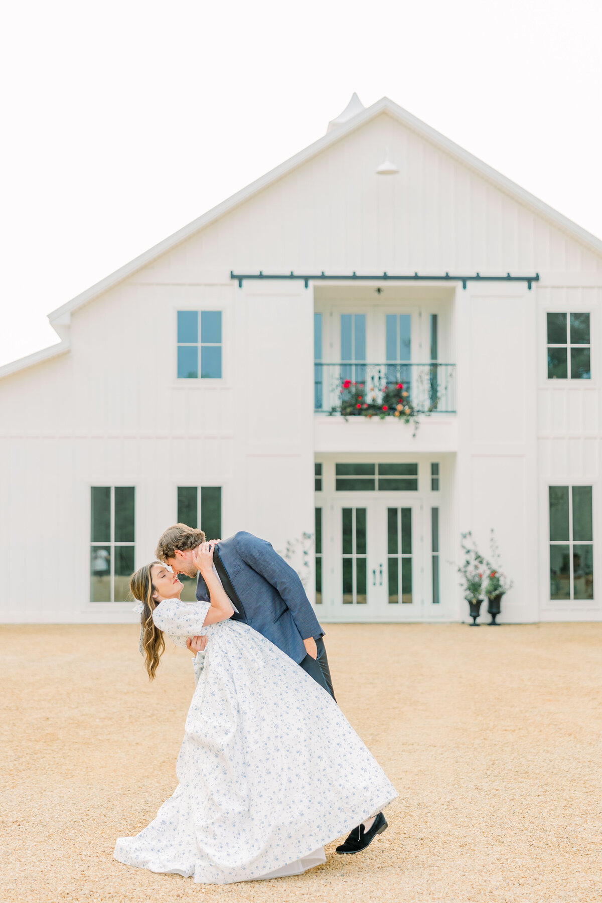 Groom dipping the bride in front of the ivy rose barn