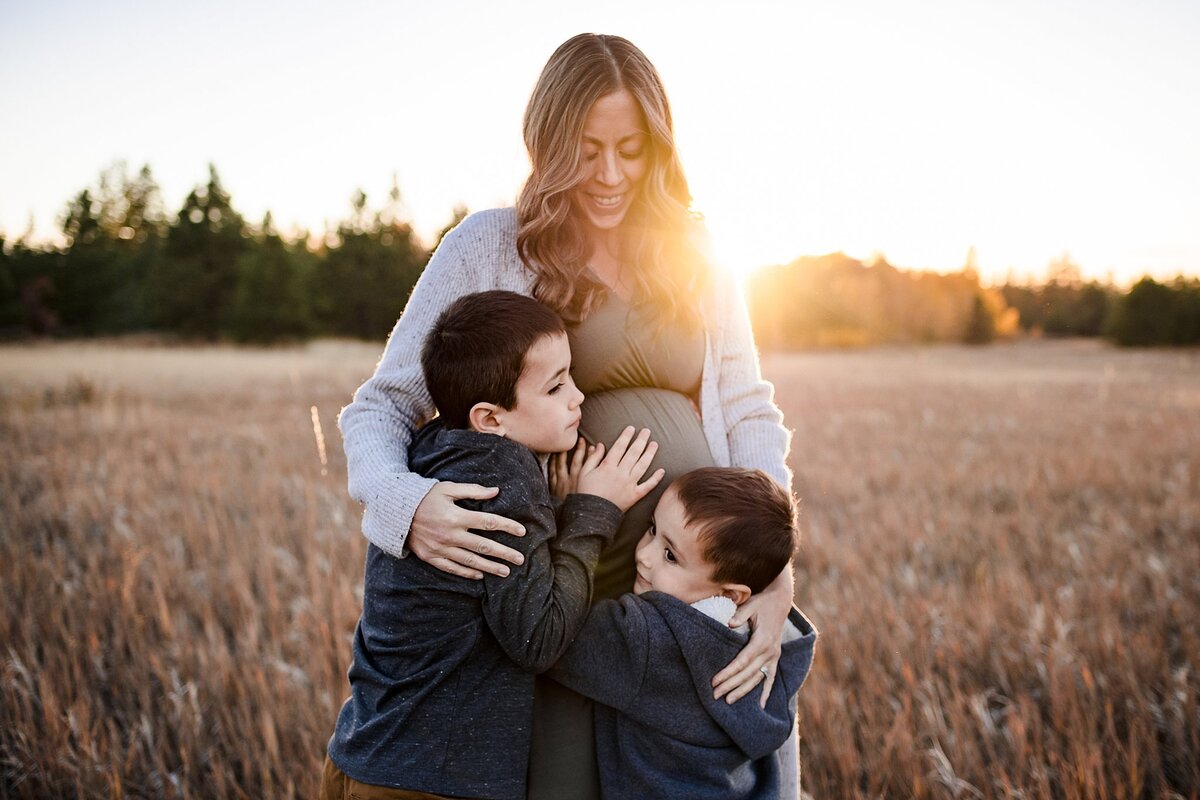 sunset maternity photos in field with mom and siblings