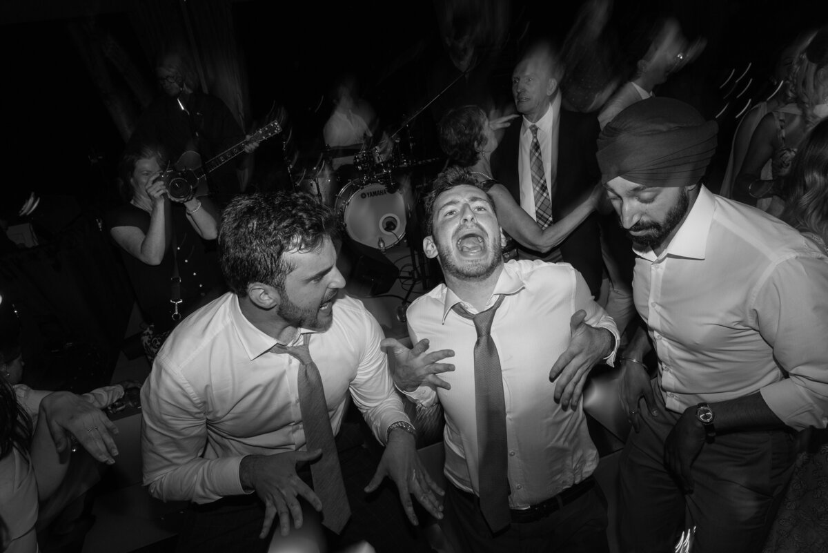 Three male guests at a wedding dancing like no one's watching