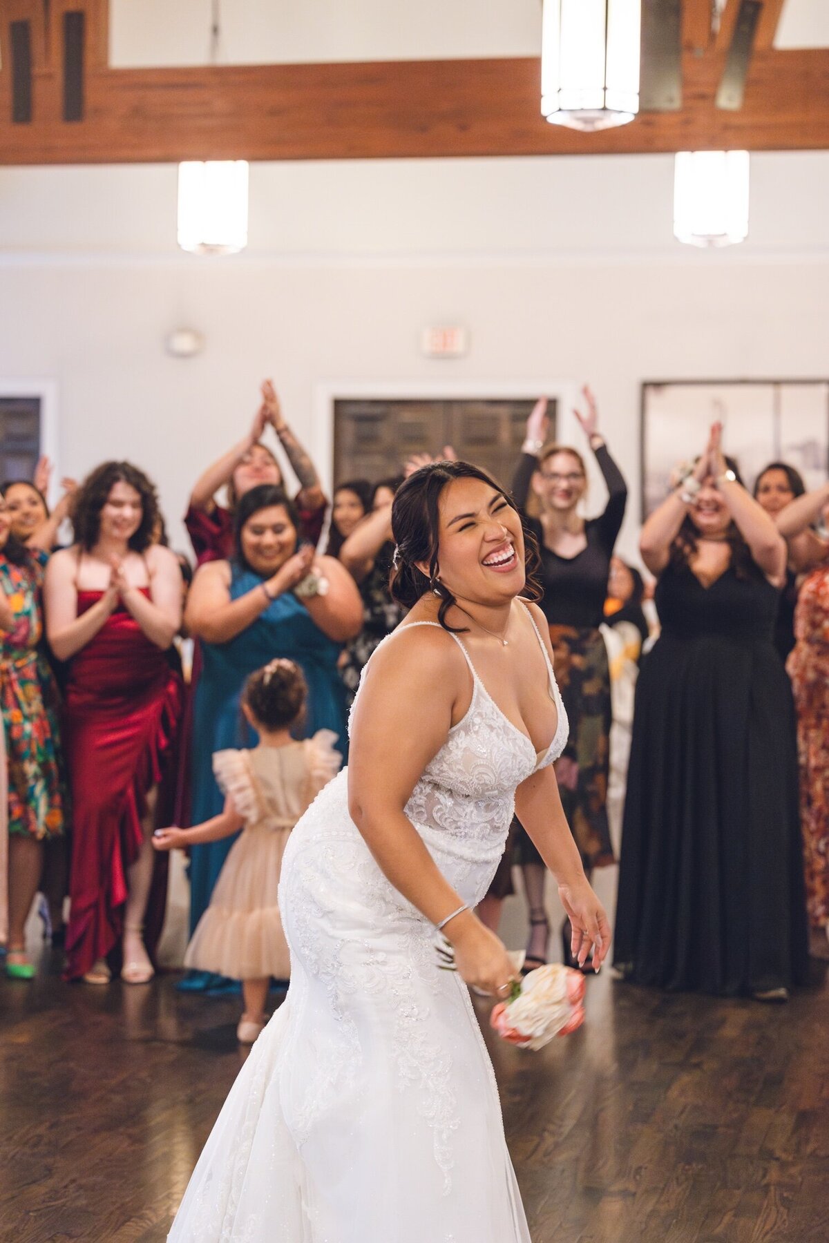 Bride tossing bouquet with guests cheering at Houston reception