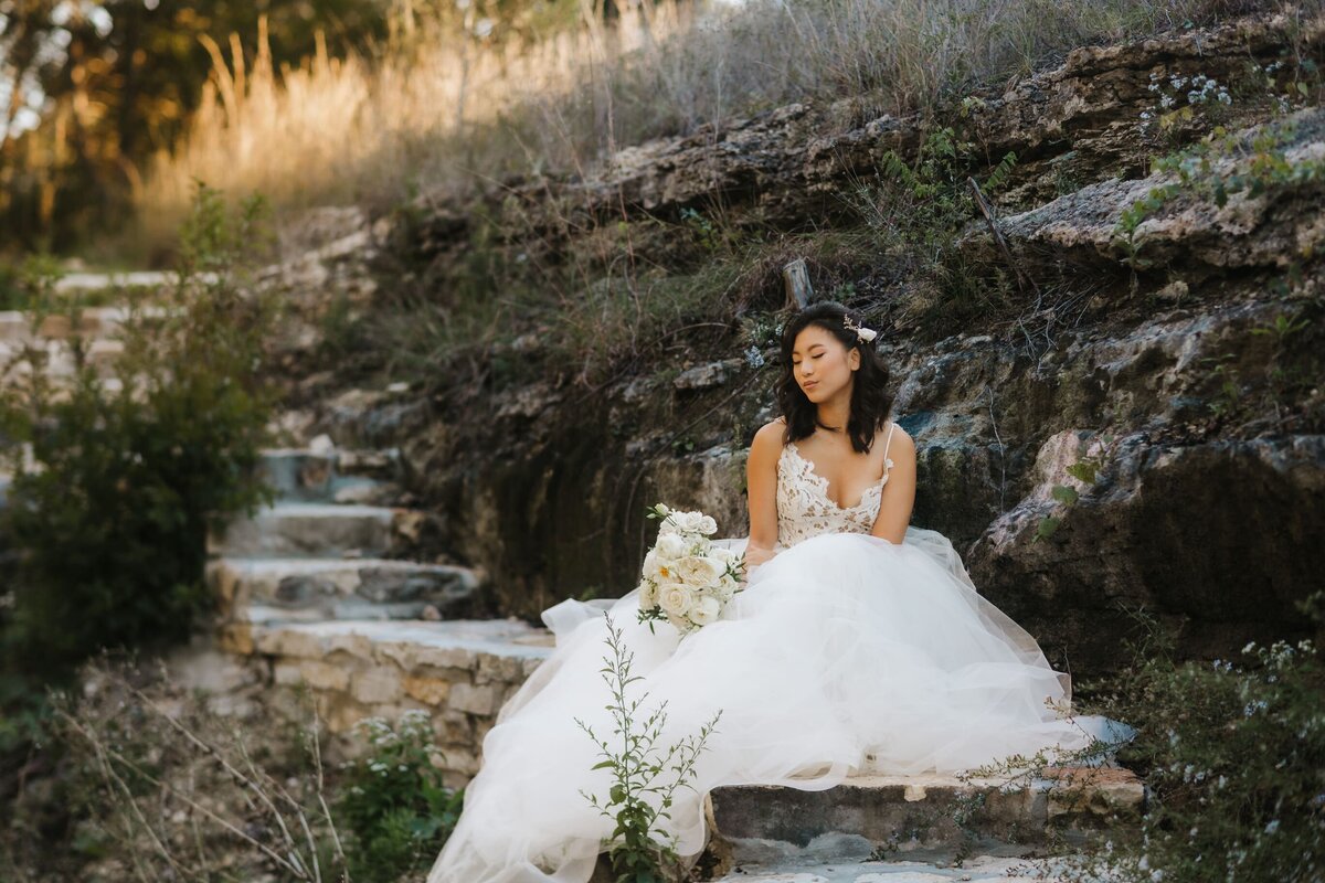 Bride sitting on steps at wedding venue in Wimberley, Texas