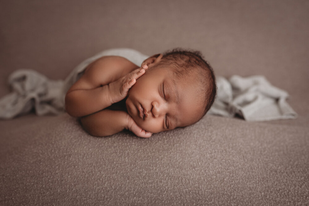 Newborn photos with Atlanta, Georgia newborn photographer of sleeping baby boy with hands under chin laying on gray fabric.