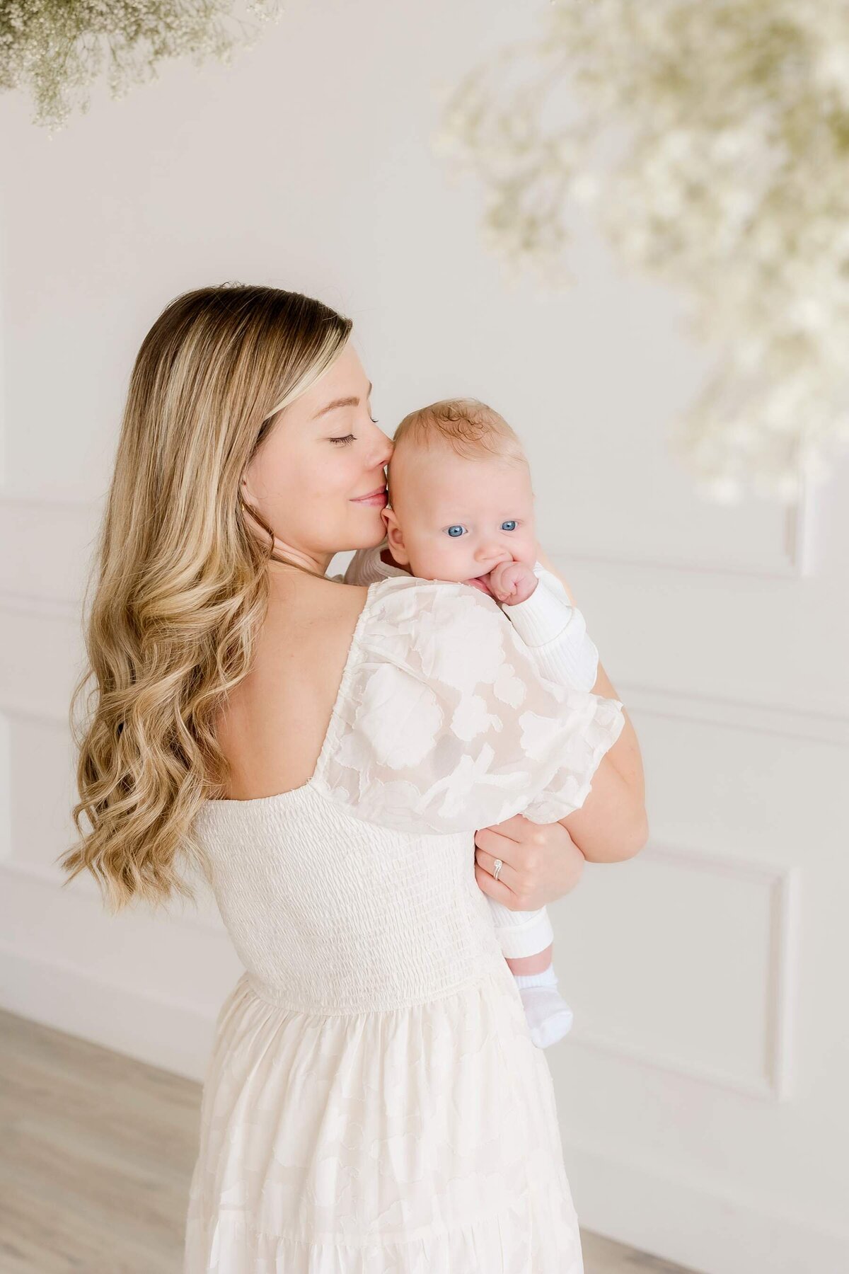 newborn son snuggled by his mom wearing all white