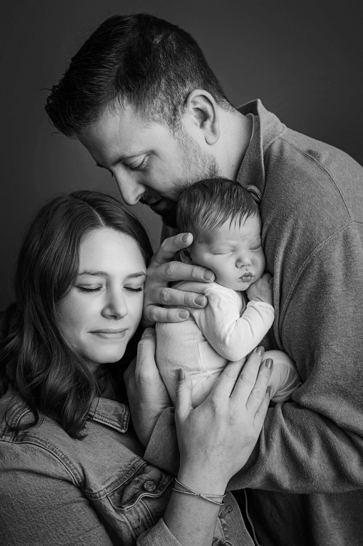 parents snuggling baby in black and white