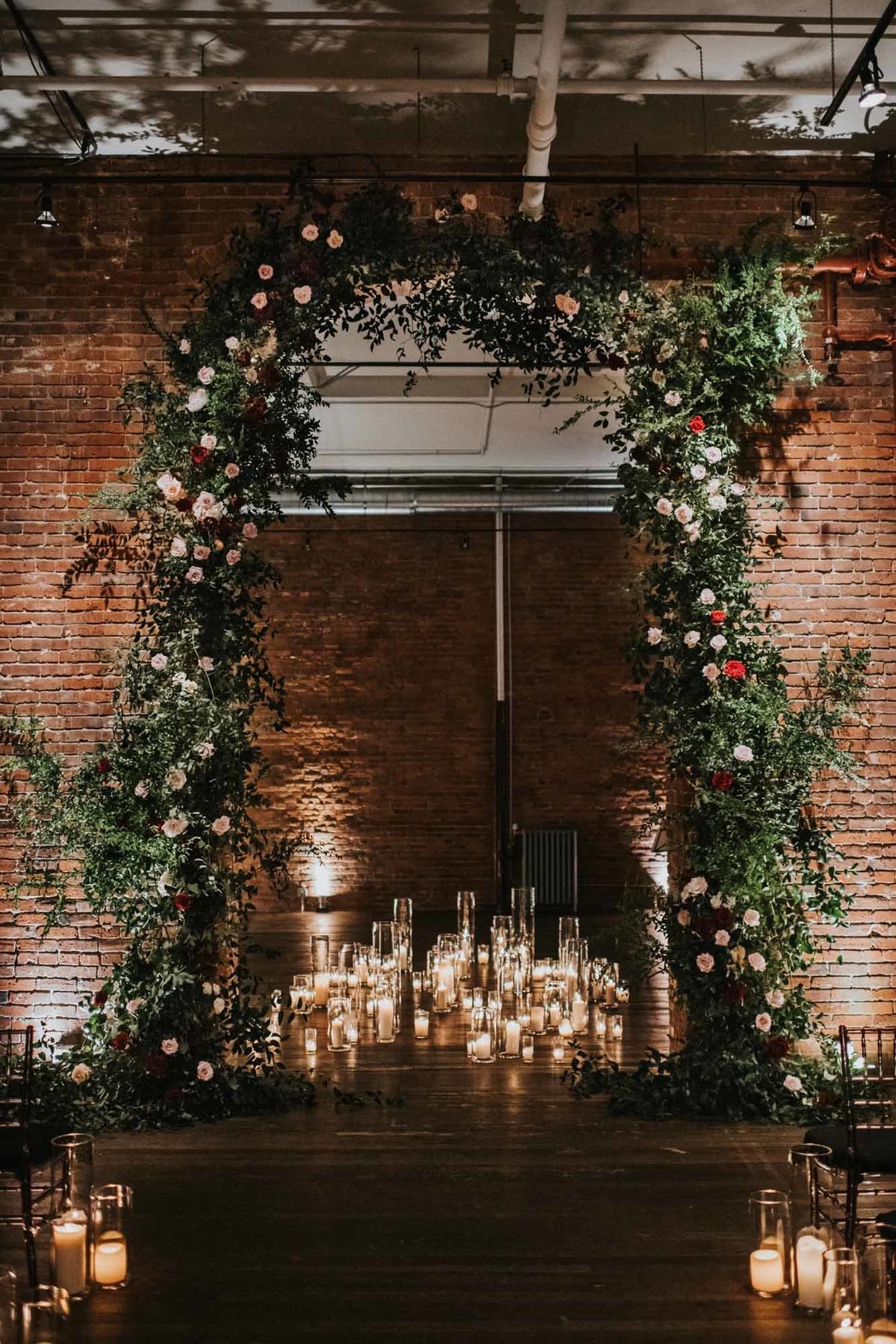 enormous greenery arch at Axis Pioneer Square with white and red blooms and hundreds of hurricane candles