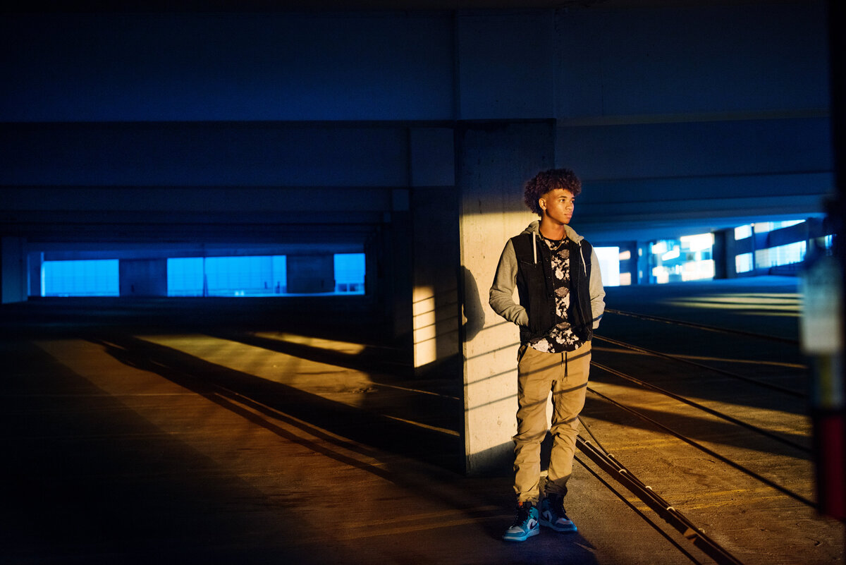 high school senior photo of boy in parking garage with lights and shadows