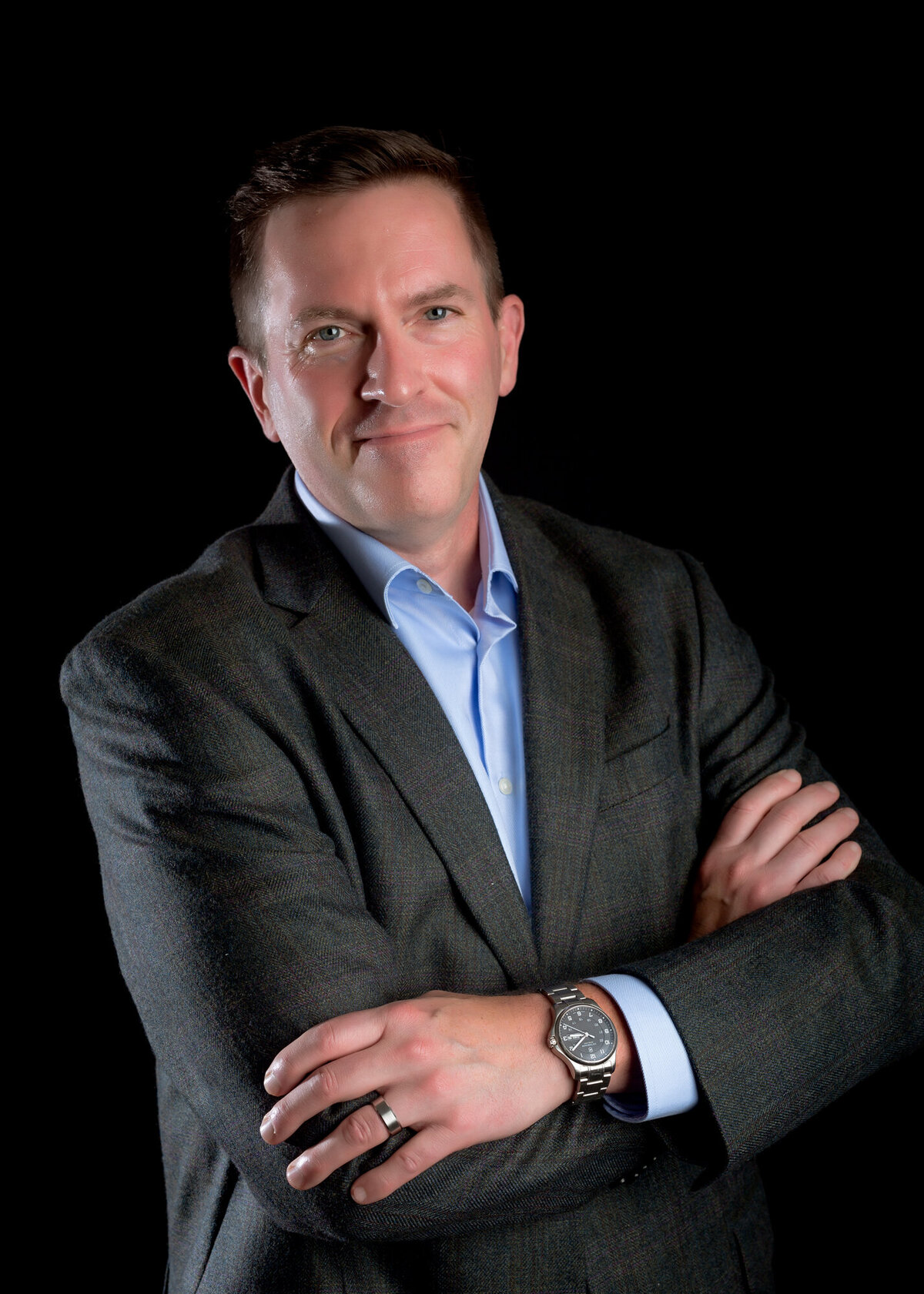 Male corporate headshot client wearing a suit, standing with arms crossed