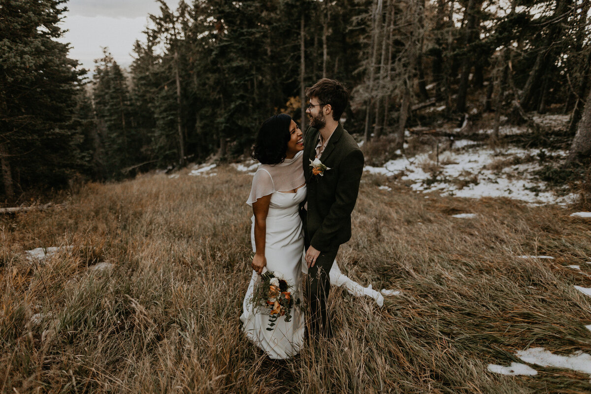 bride and groom holding each other on a mountain slope in NM