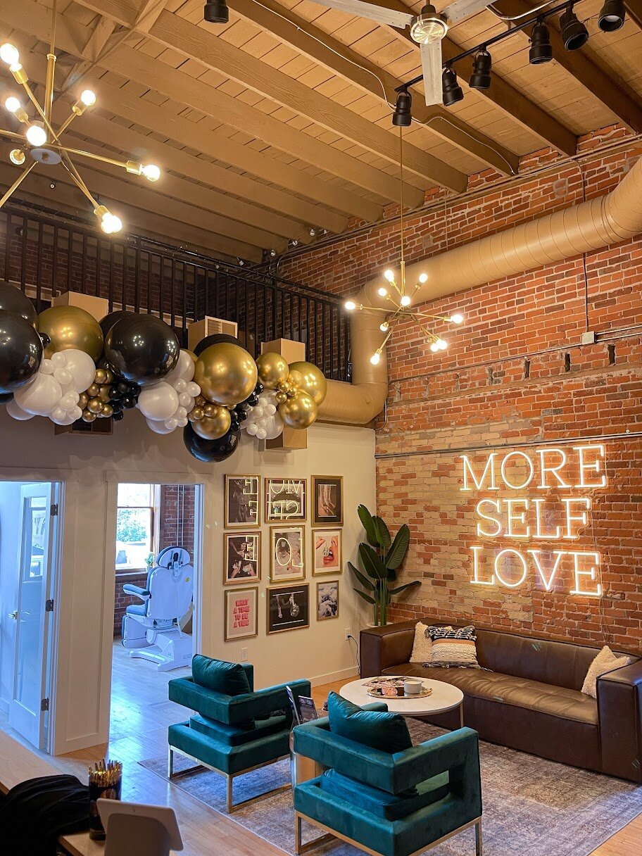 A black, gold, and white balloon garland hanging on the wall inside a business.