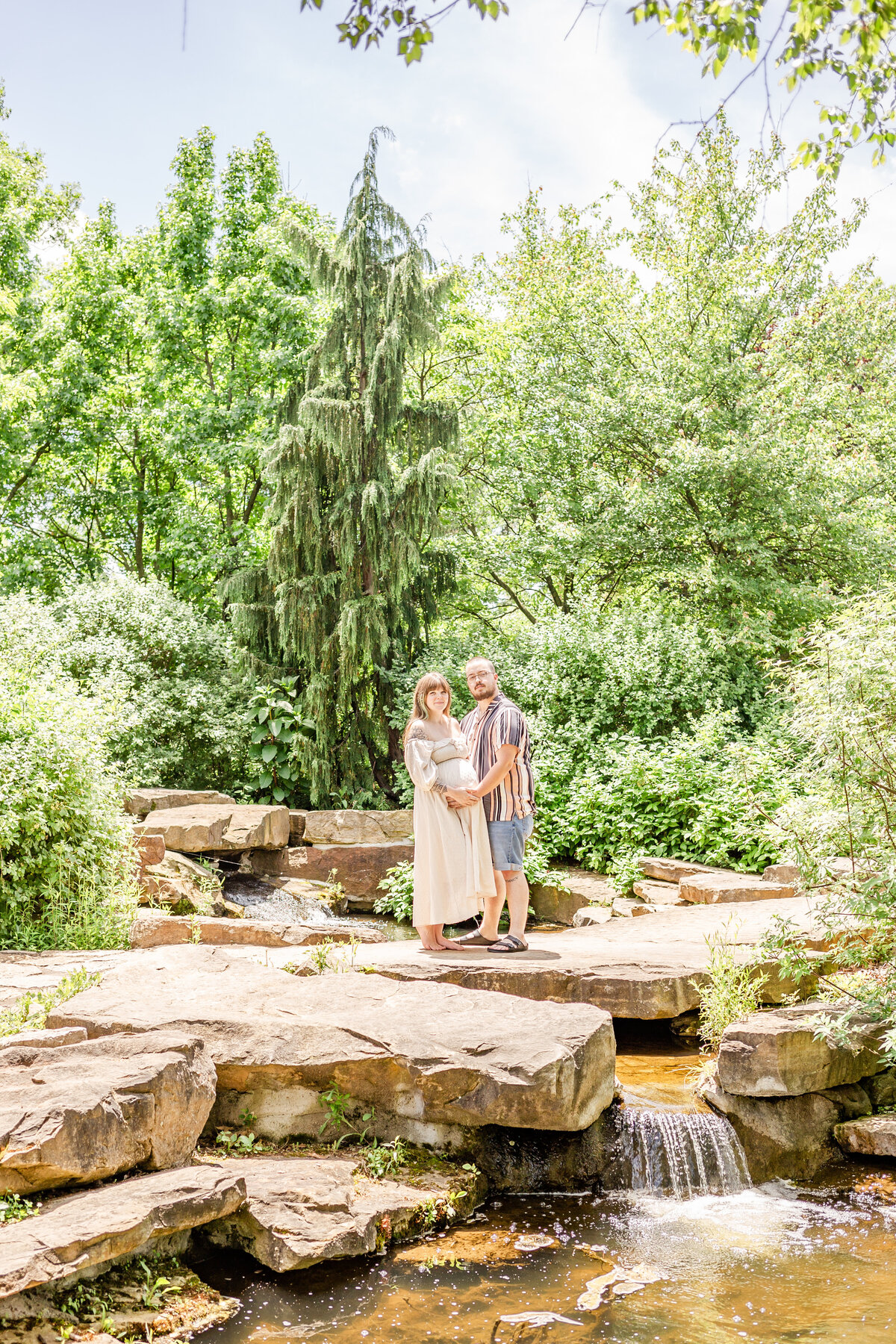 Bright summer maternity photo cuddling baby belly at Cox Arboretum in Miamisburg, Ohio.