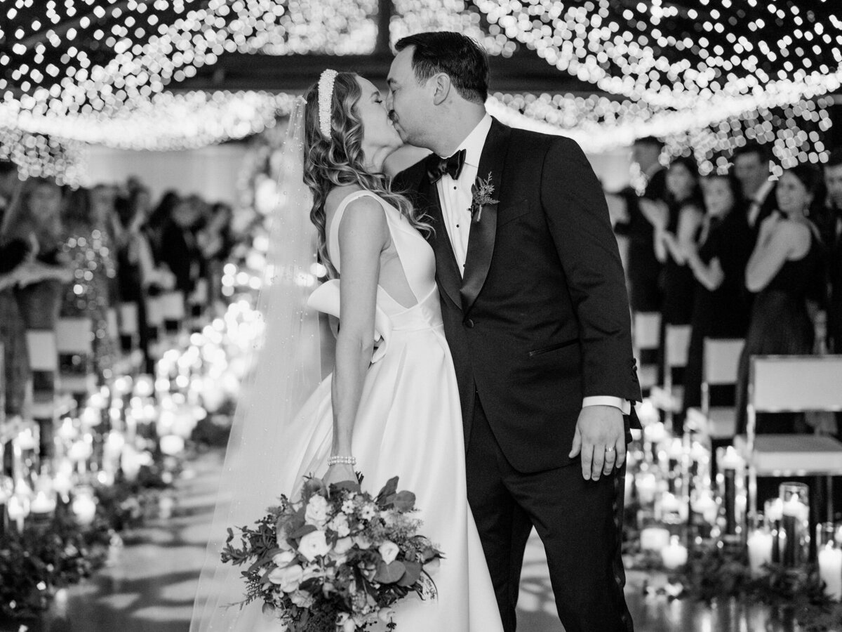 Black and white photo of the bride and groom sharing a kiss at the the Theater on the Lake. 
