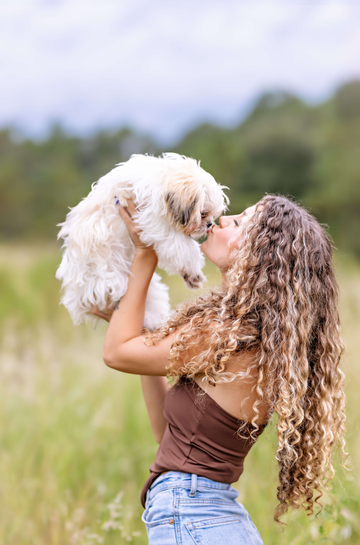 Candid Windermere senior photo with a teen girl kissing her dog during golden hour.