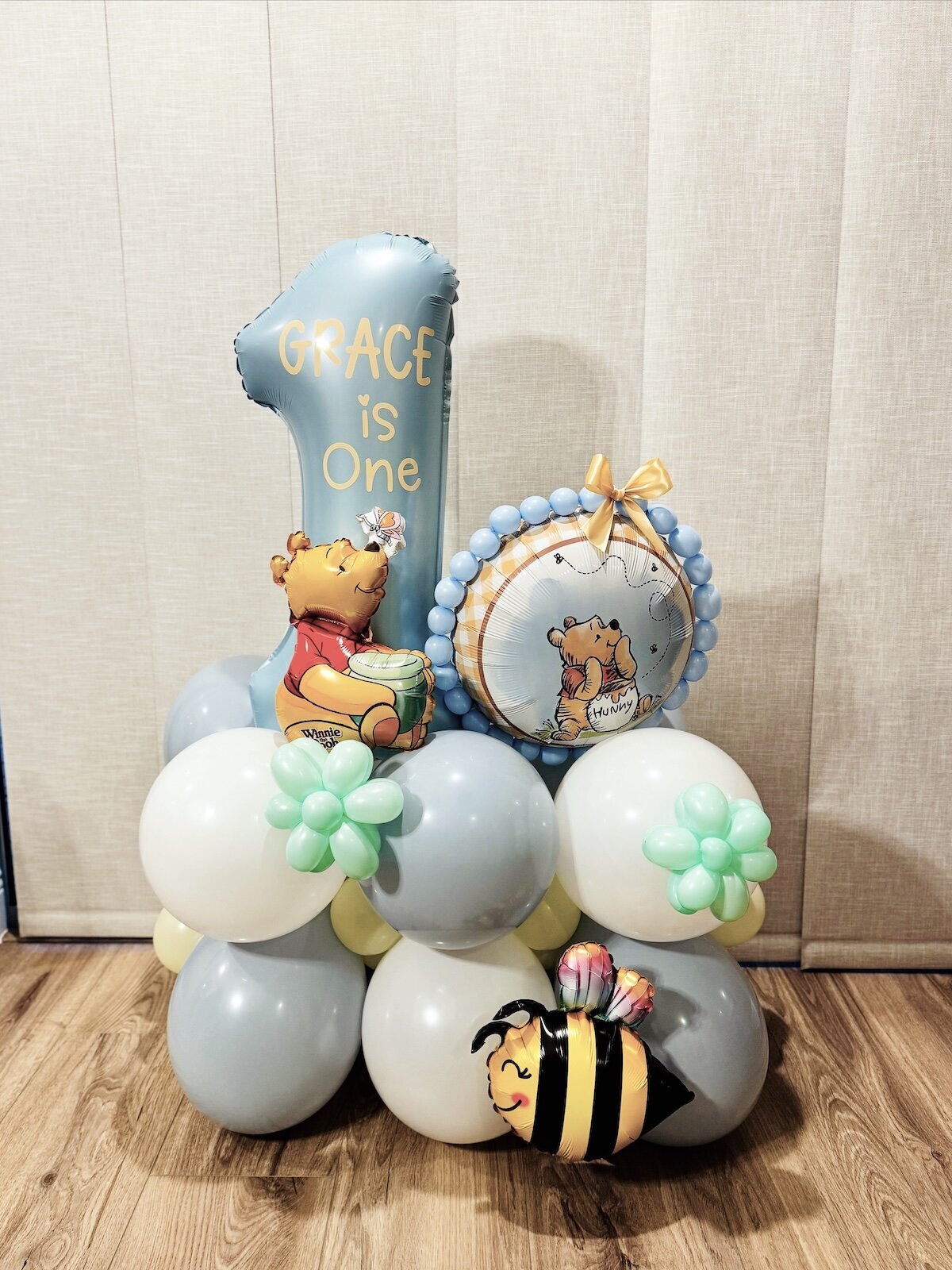 Winnie the Pooh Balloon Bouquet with light blue, white and silver balloons for a 1st birthday.