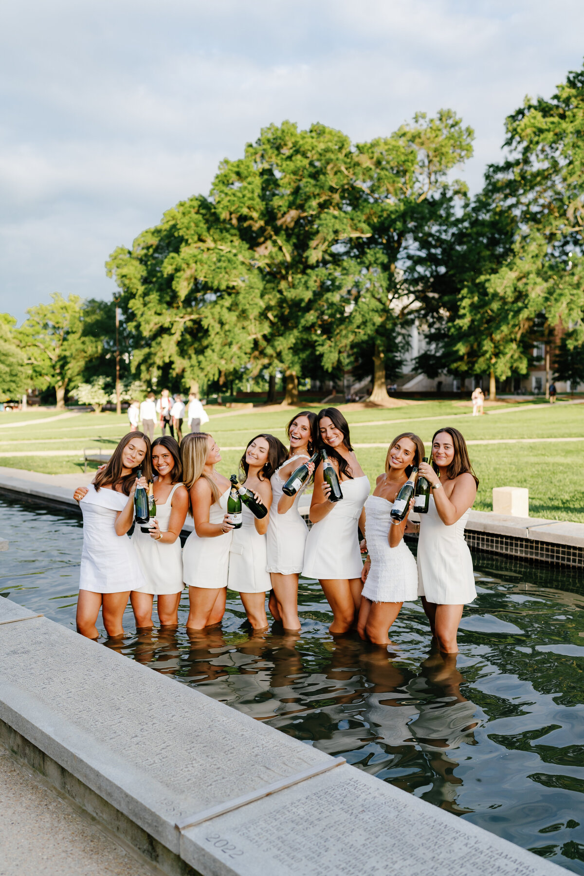 University of Maryland Graduates in the fountain at McKeldin Mall in College Park Maryland Captured by UMD Graduation Photographer Brenna Marie Photography