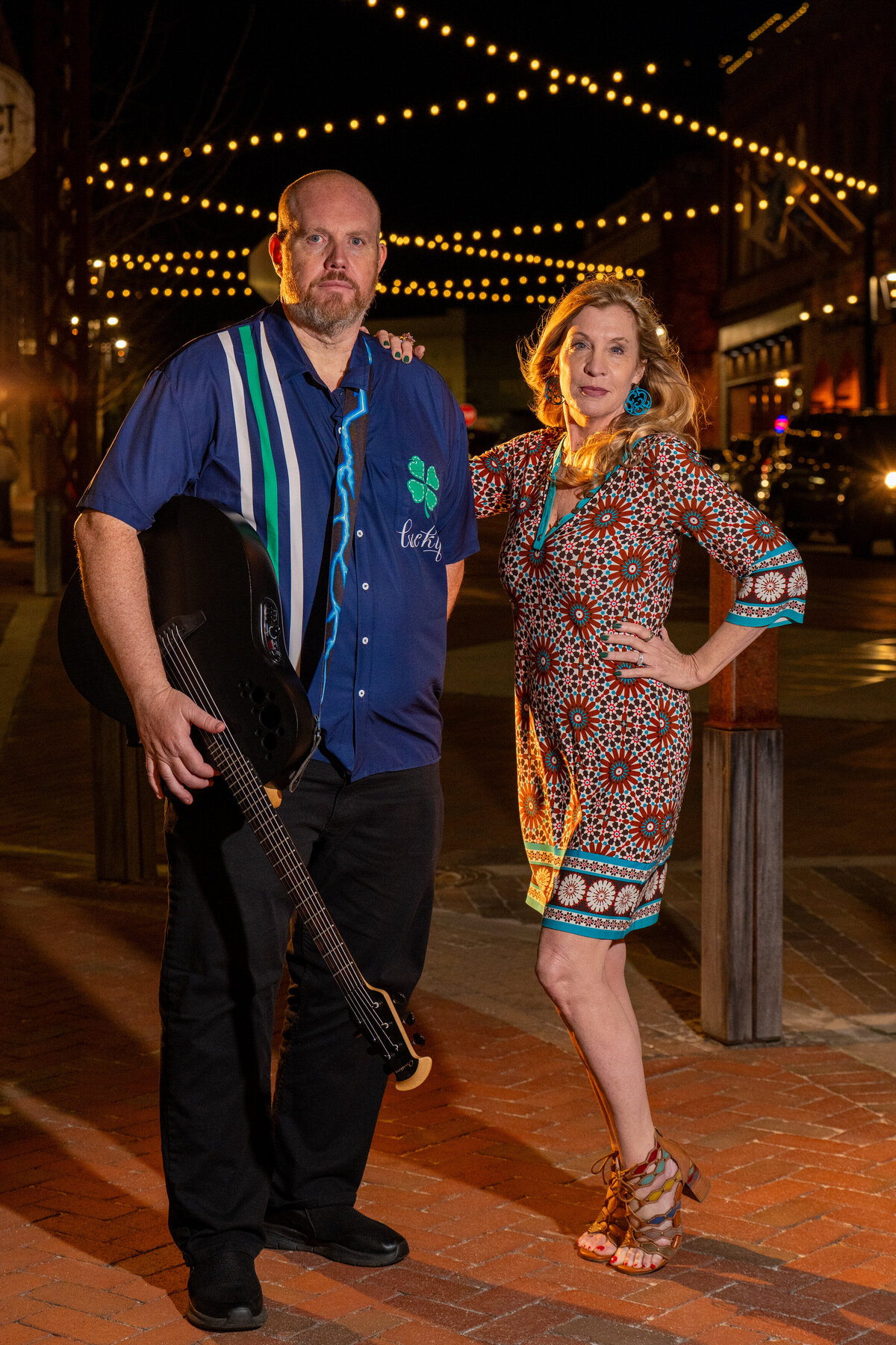 Two people standing together while one holds a guitar 