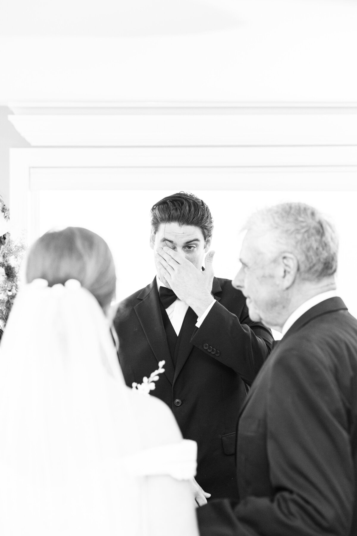 Groom wiping away a tear as his bride walks down the aisle representing candid Boston wedding moments