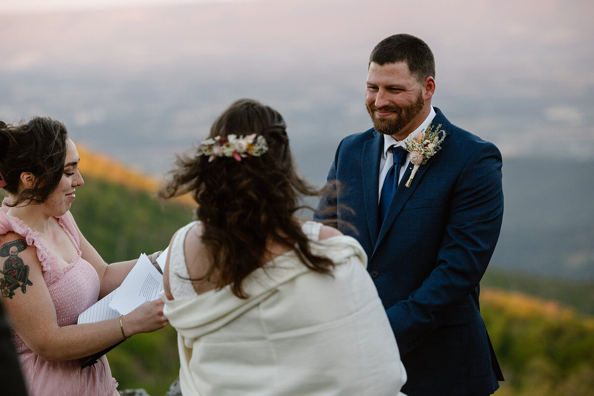 A groom smiles at his bride while they exchange vows during their sunrise ceremony at Shenandoah National Park