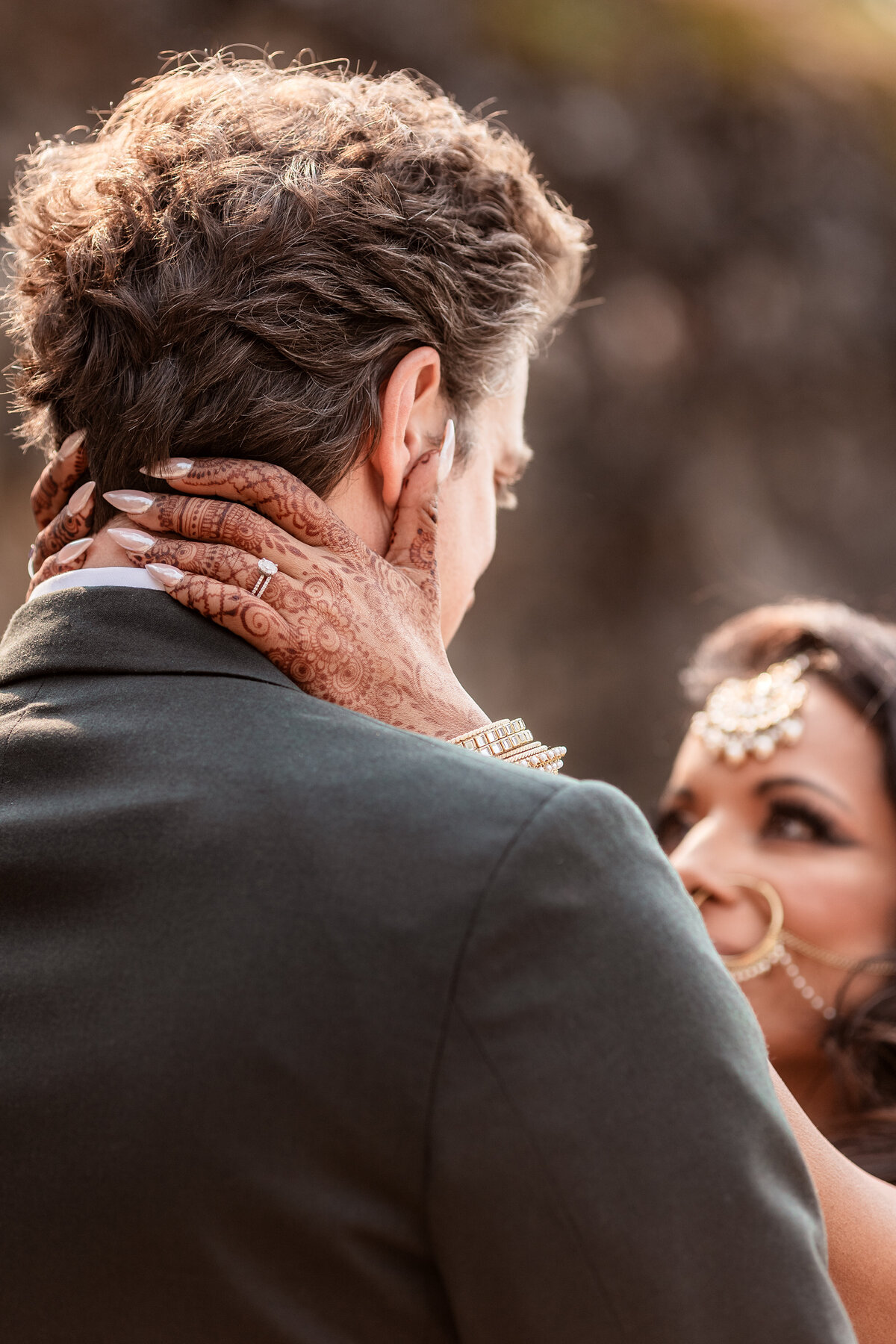 Brides hand with henna in focus on her husbands neck