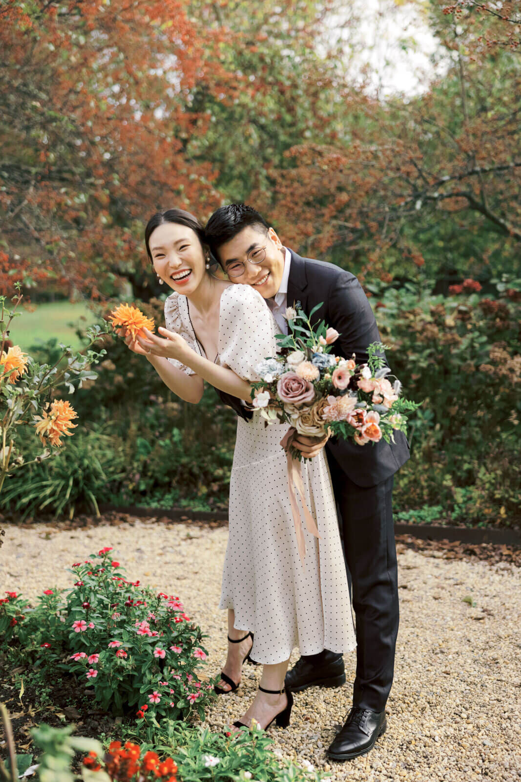 The man is hugging his fiance from behind amidst the flower-filled garden at Planting Fields Arboretum, NY. Image by Jenny Fu Studio