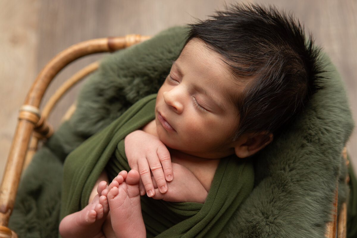 Edmonton newborn photography backlit baby wrapped in a basket with sage green pose