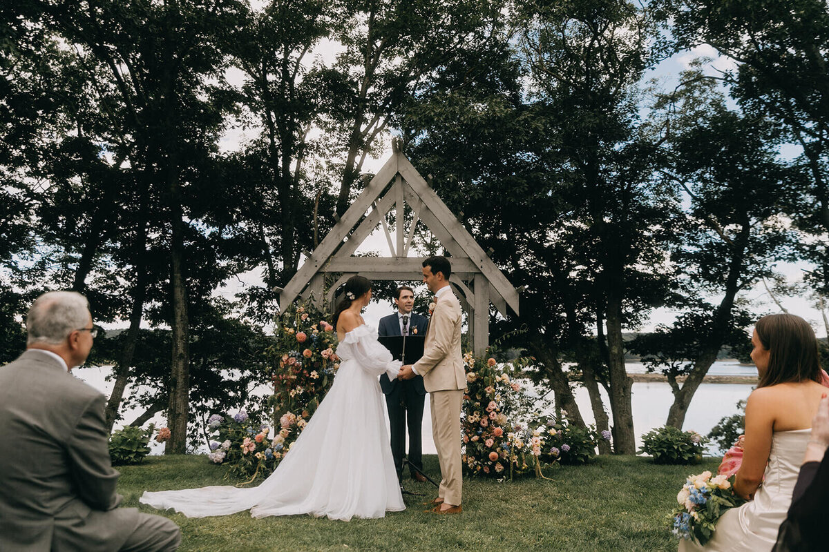 28.bride-and-groom-vows-outdoor-wooden-arch-pastel-wedding-flowers