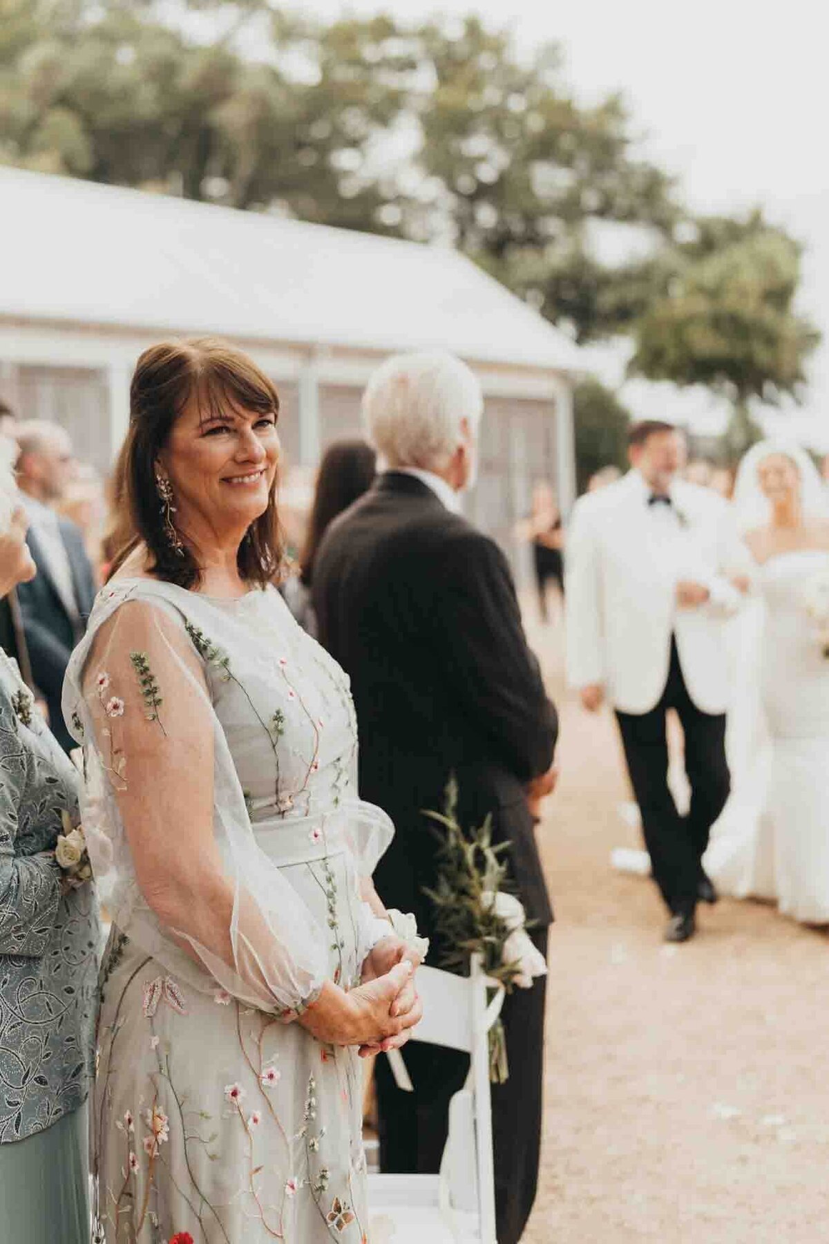 mother looks at her son, watching his bride walk down the aisle with her father.