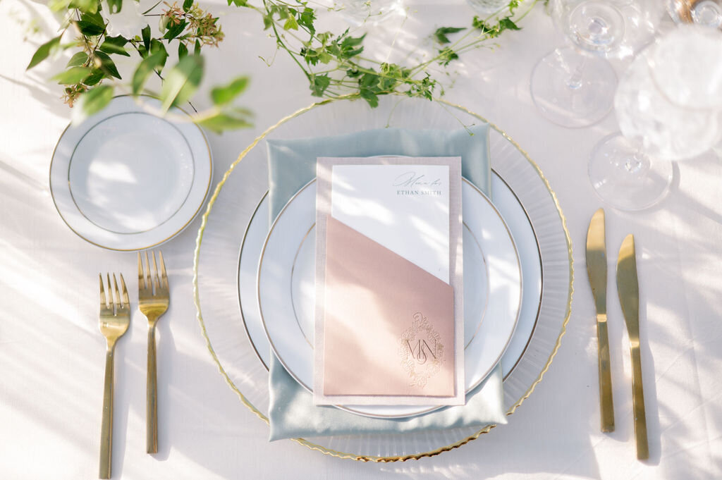 Wedding reception table that has dinnerwares and custom menu calligraphy