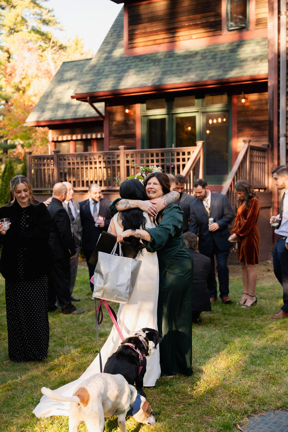 The bride shares a hug with one of her bridesmaids during a backyard wedding in the Adirondacks at the Sagamore Golf House.