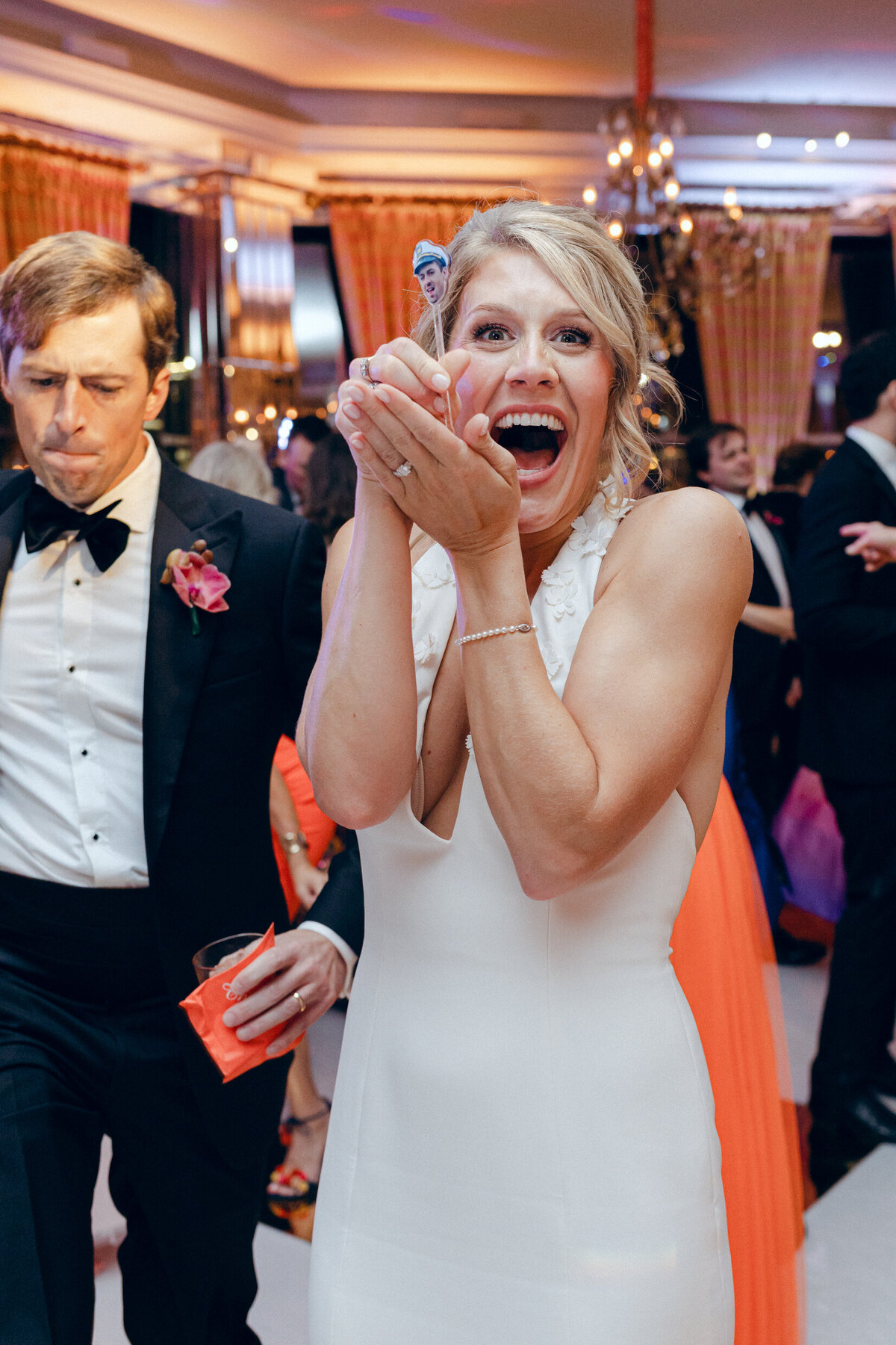 A candid wedding day photo of the bride smiling in excitement during her wedding reception