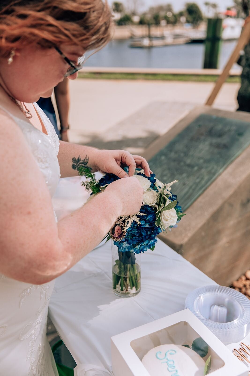 Bride placing a photo of her deceased brother in her bouquet