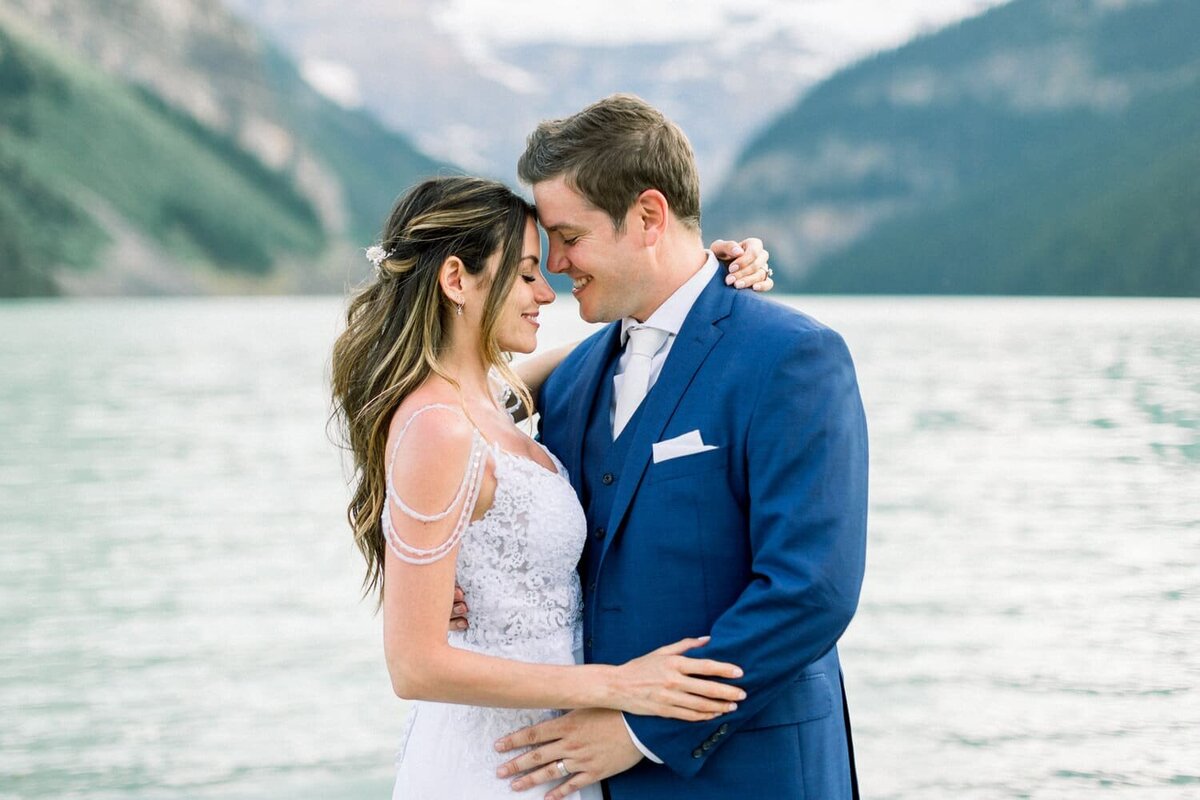 groom-smiling-as-he-holds-his-bride-at-Lake-Louise-Alberta