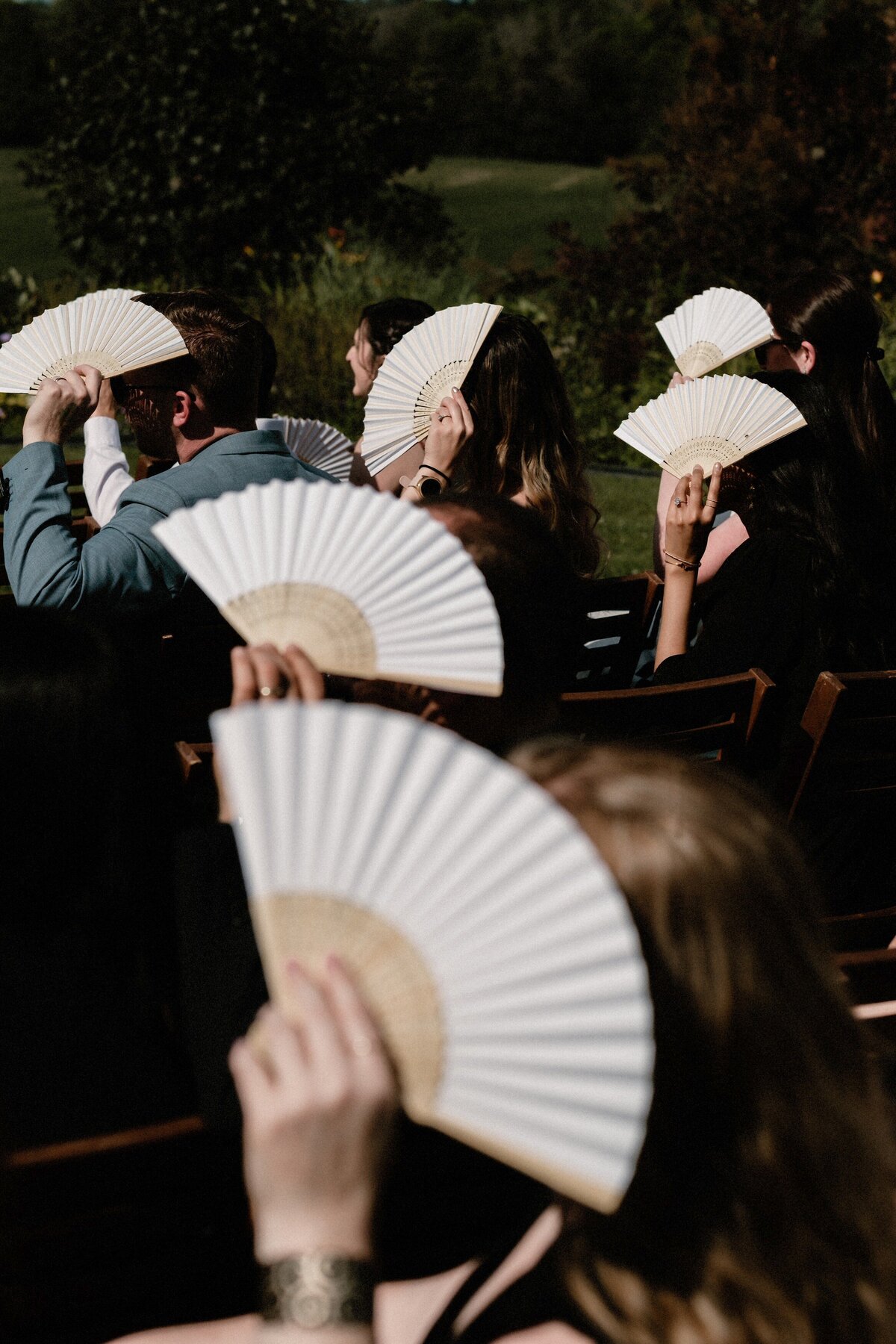 guests waving fans to shade themselves from the sun during this ceremony