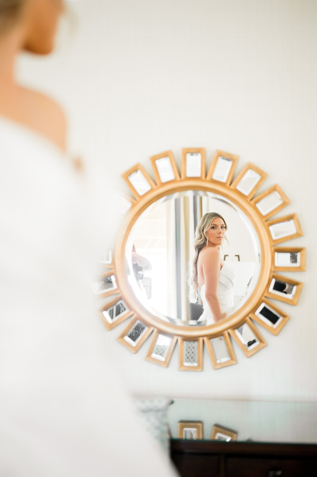 bride looking at herself in a round mirror on wedding day
