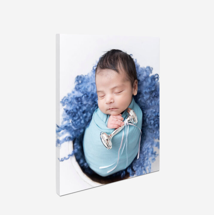A fine art newborn photo printed on canvas on a wall
