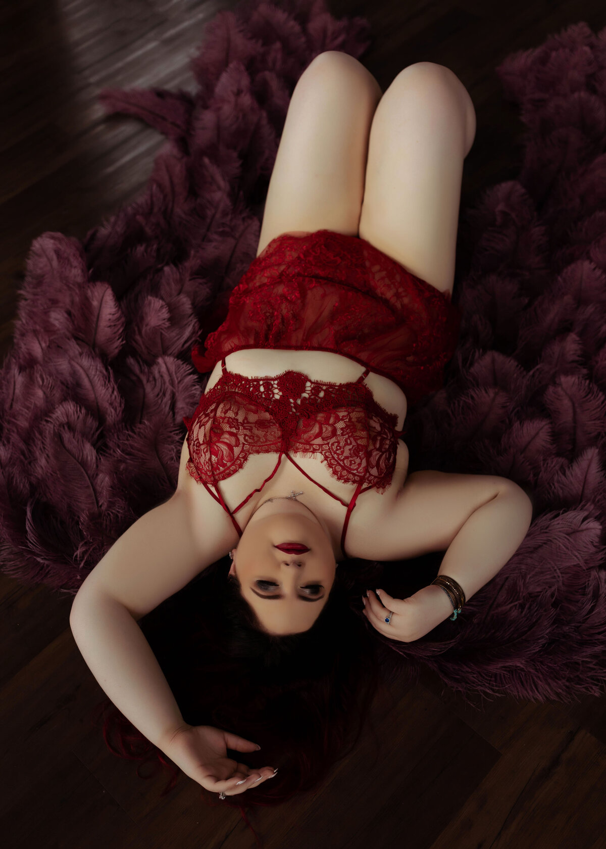 plus size boudoir woman wearing red lingerie and purple angel wings