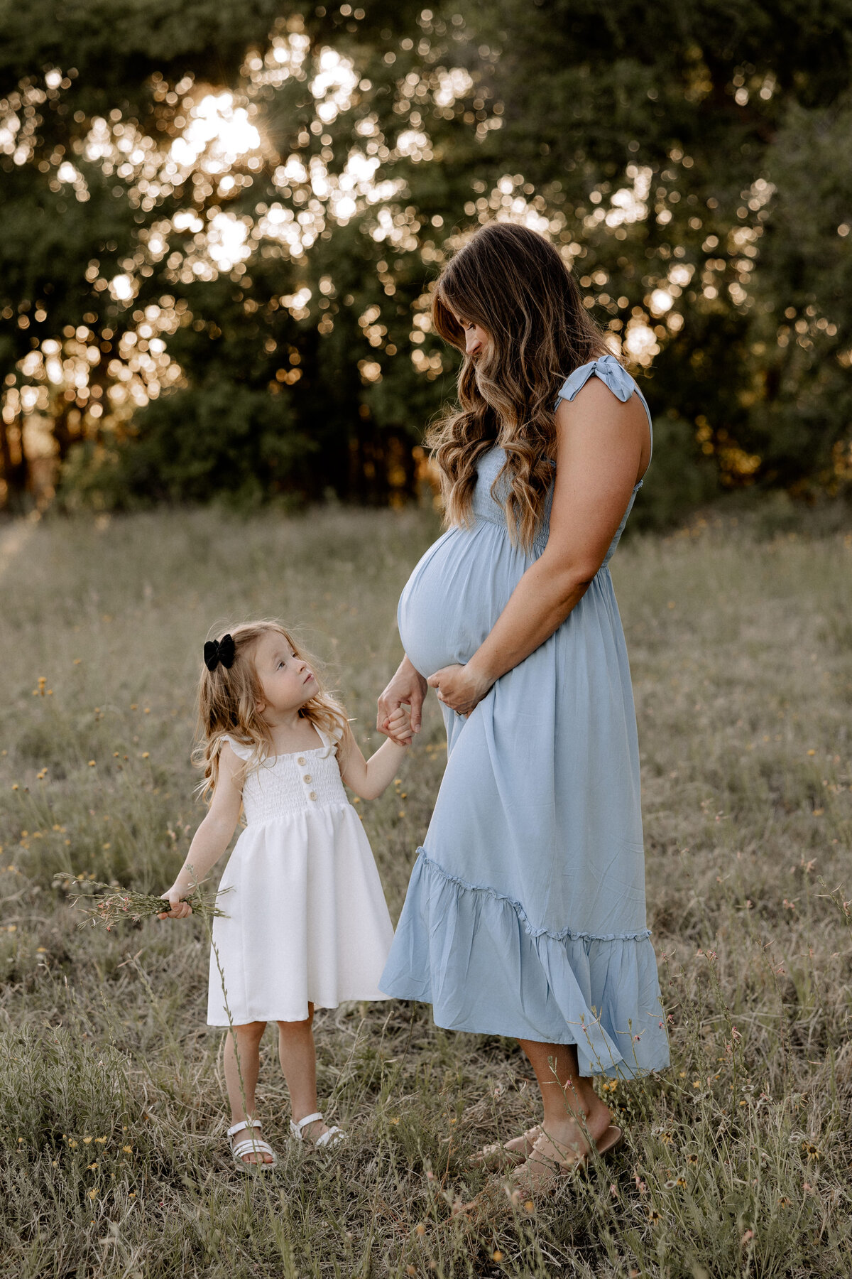 mama in blue maternity dress holding big sisters hand