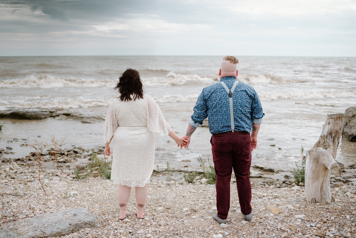 lake erie elopement bride and groom hold hands on the shore of lake erie