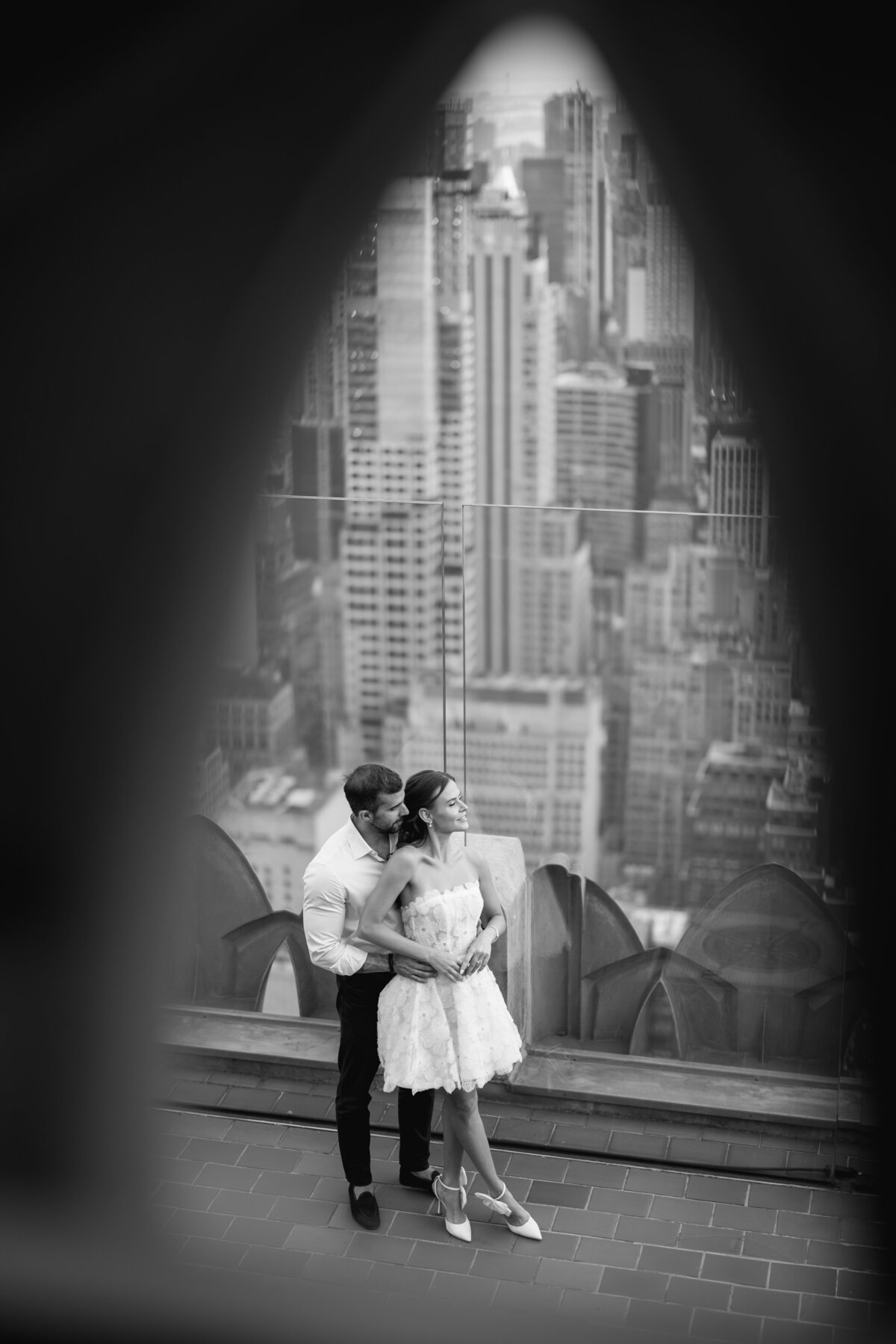 A breathtaking moment as the bride and groom share an intimate embrace with the stunning NYC skyline in the background, captured at The Rockefeller Center.