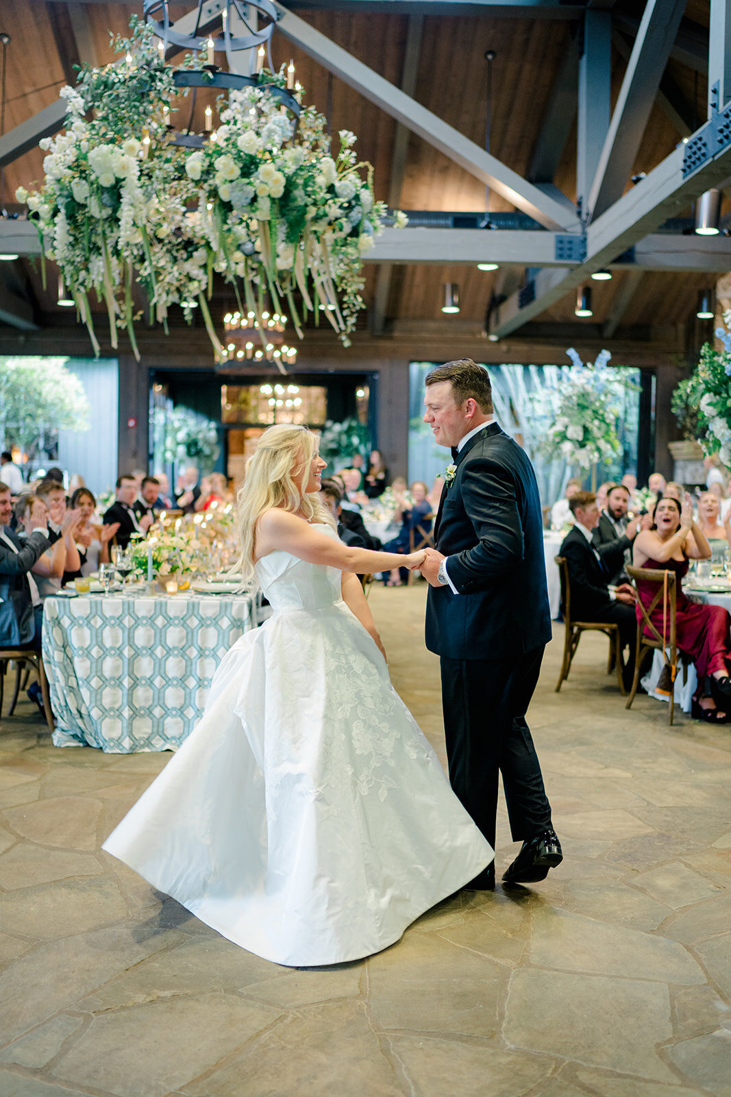  Bride and groom dancing under hanging floral chandeliers at a romantic wedding reception in Highlands, North Carolina.