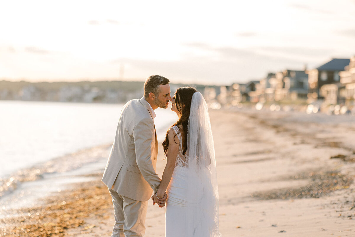 A peaceful moment as the couple stands face to face on the beach, with the setting sun casting a warm glow over the serene scene.