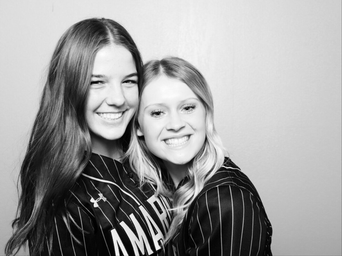 two softball players smiling for a photo booth picture
