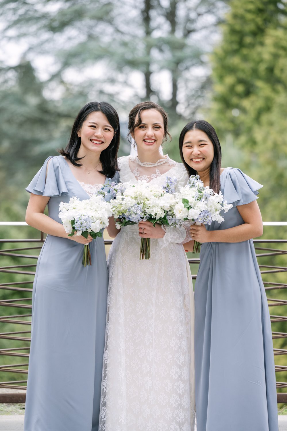 bride with bridesmaids in powder blue gowns outside